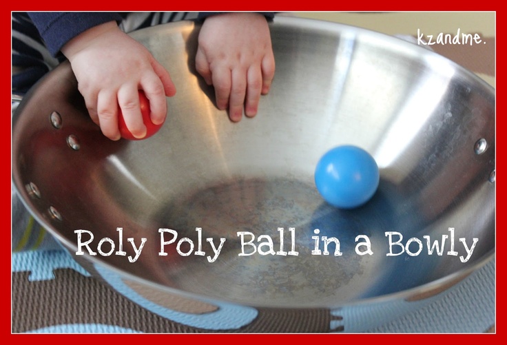 This may contain: a baby playing in a metal bowl with a blue ball on the bottom and words that read, roll poly ball in a bowl