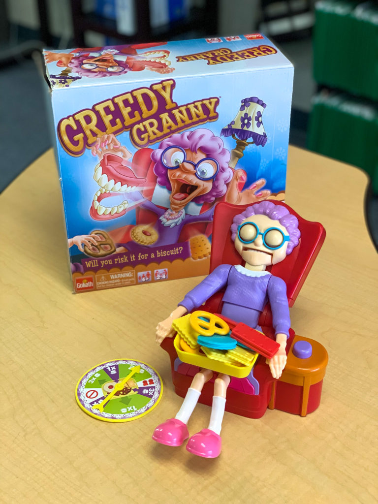 This is a photo of the game Greedy Granny.  The granny is sleeping in her chair with a plate of snacks.  There is a spinner.