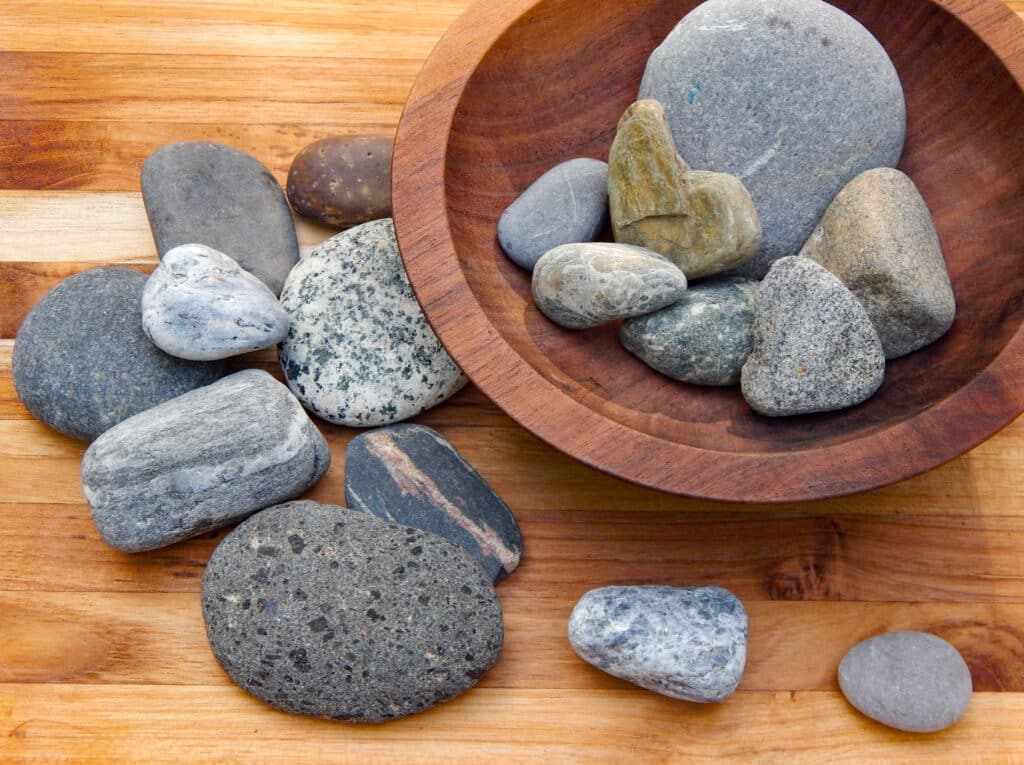 sorting bin with river and beach rocks in a wooden bowl variety of shapes, sizes, and patterns