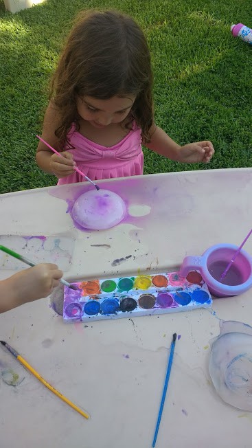 Little girl painting on Ice with water color.