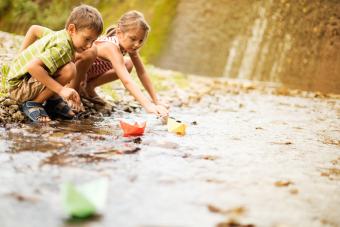 Boy and girl playing paper boats on the river