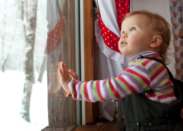baby looking out window in winter