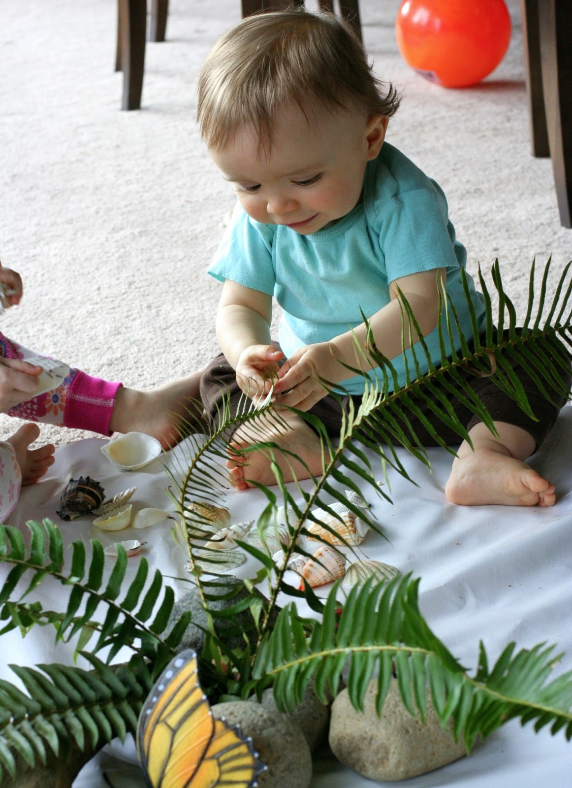 This may contain: a baby is sitting on the floor playing with some kitchen utensils in a basket